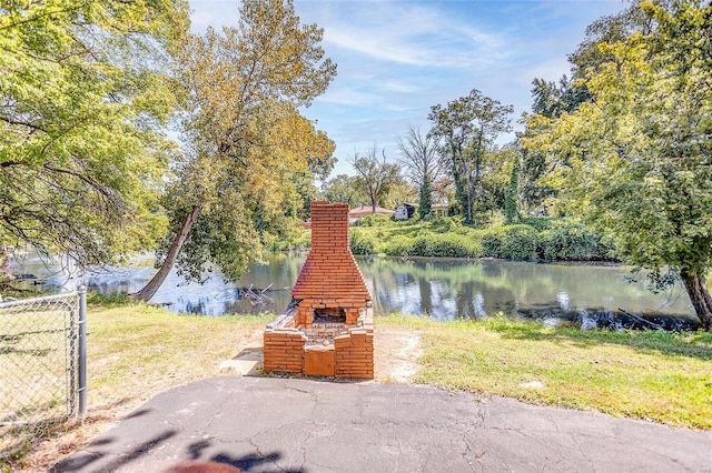 view of patio with a water view and an outdoor brick fireplace