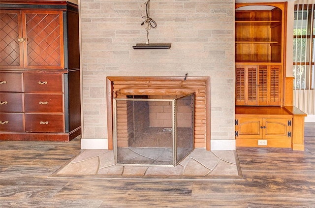 room details with built in shelves, a multi sided fireplace, and wood finished floors