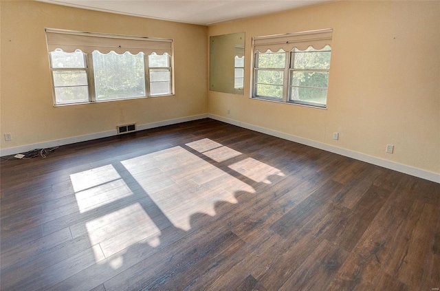 unfurnished room featuring baseboards, visible vents, and wood finished floors