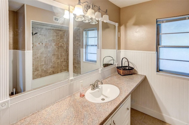 bathroom with a wainscoted wall, tile patterned flooring, and a wealth of natural light