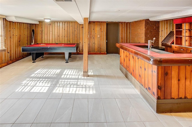 playroom featuring light tile patterned floors, a bar, and wood walls