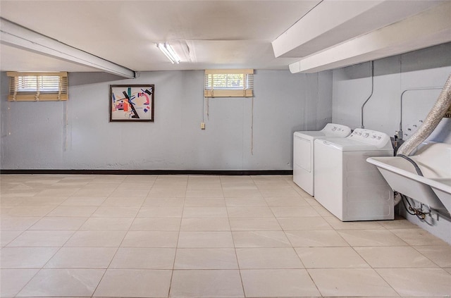 washroom featuring light tile patterned floors, laundry area, a sink, baseboards, and independent washer and dryer