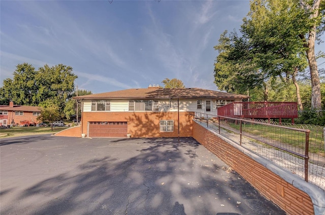 view of front of house with driveway, brick siding, an attached garage, and fence