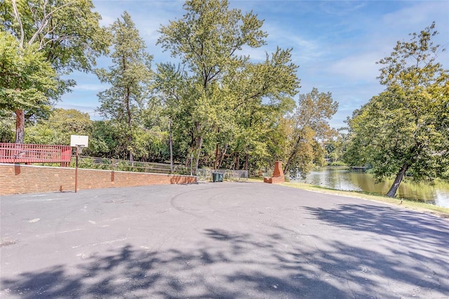 view of basketball court with a water view and fence