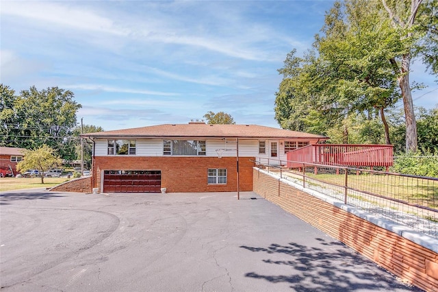 view of front of house featuring a garage, driveway, brick siding, and fence