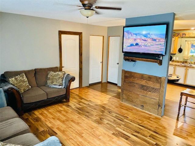 living room featuring light hardwood / wood-style flooring, sink, and ceiling fan