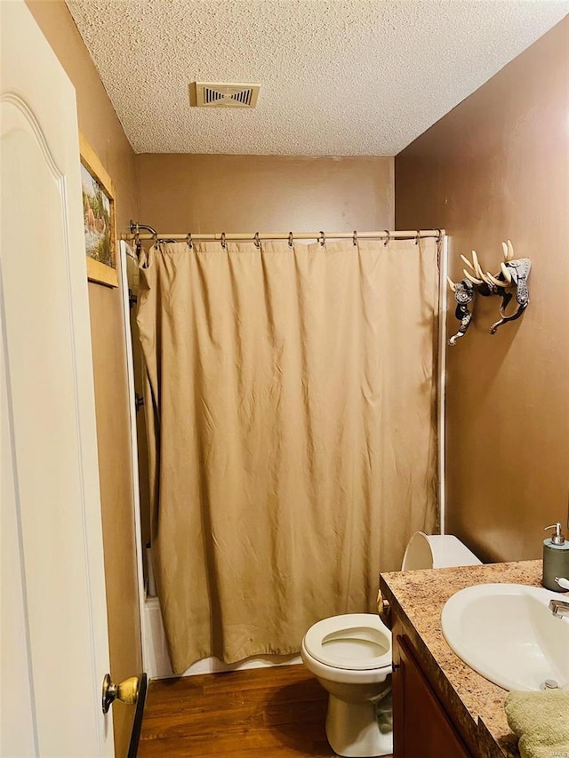 full bathroom featuring a textured ceiling, wood-type flooring, toilet, vanity, and shower / tub combo with curtain