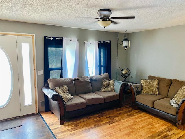 living room featuring ceiling fan, wood-type flooring, and a textured ceiling