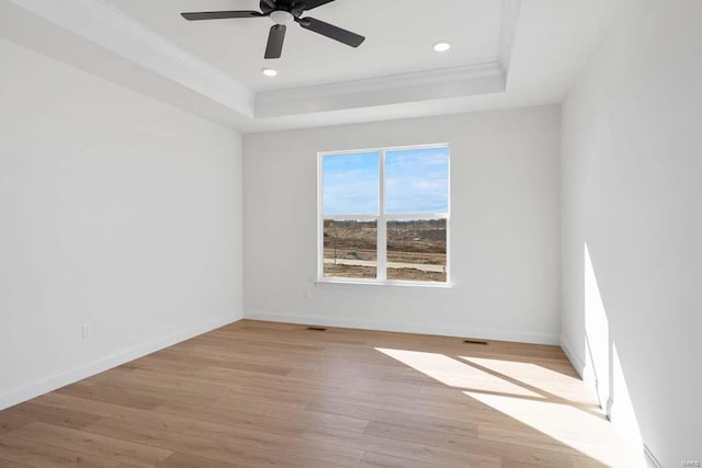 unfurnished room featuring baseboards, crown molding, a tray ceiling, and wood finished floors