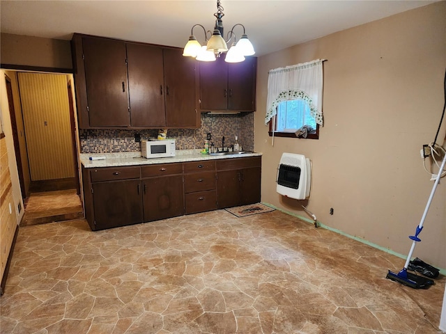 kitchen with stone finish floor, a sink, heating unit, and white microwave