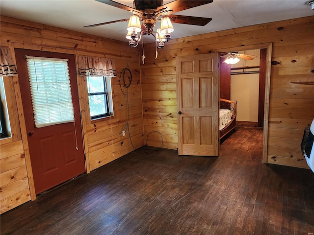 interior space featuring dark wood-style floors, ceiling fan, and wooden walls