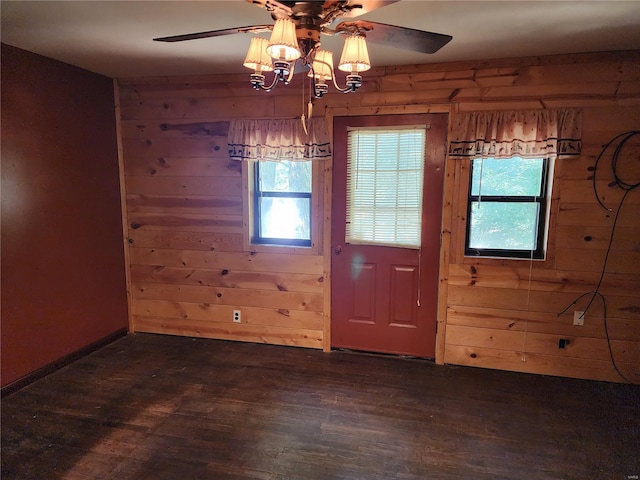 interior space with wood walls, ceiling fan, dark wood finished floors, and a wealth of natural light