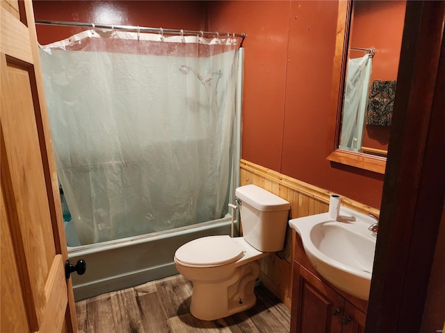 bathroom featuring wainscoting, toilet, wood finished floors, shower / tub combo with curtain, and vanity