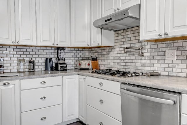 kitchen featuring appliances with stainless steel finishes, light stone counters, decorative backsplash, and white cabinets