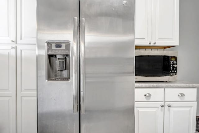 kitchen with stainless steel fridge with ice dispenser and white cabinetry