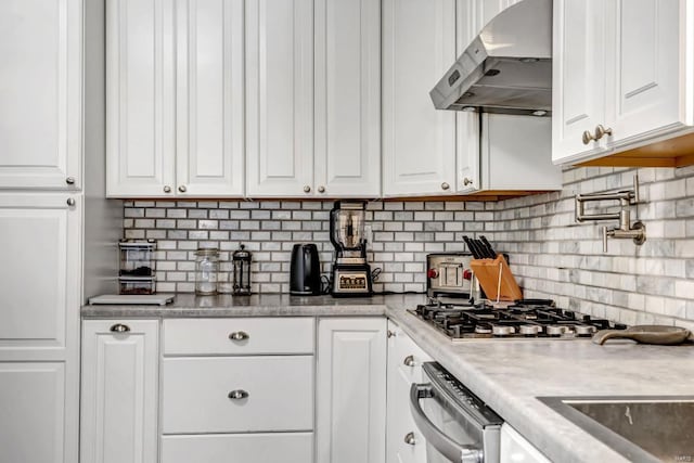 kitchen with wall chimney range hood, backsplash, and white cabinetry