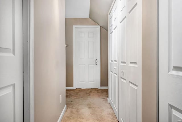 hall with light colored carpet and vaulted ceiling