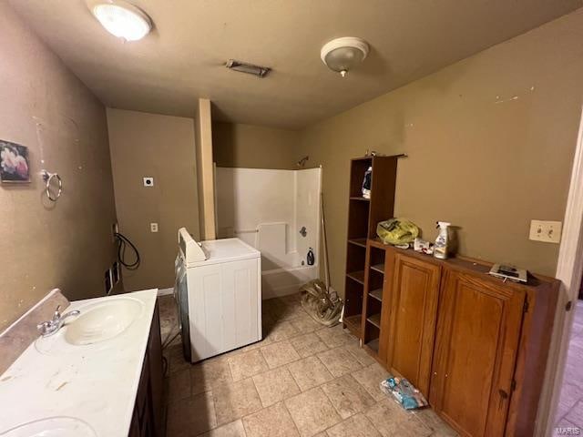 bathroom featuring washer / dryer, bathing tub / shower combination, and vanity