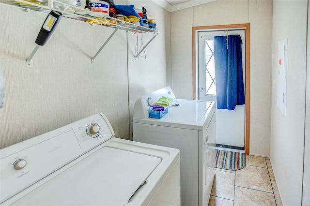 clothes washing area with washing machine and dryer, crown molding, and light tile patterned floors