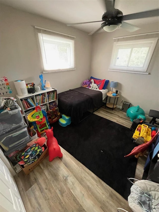 bedroom featuring ceiling fan, wood-type flooring, and multiple windows