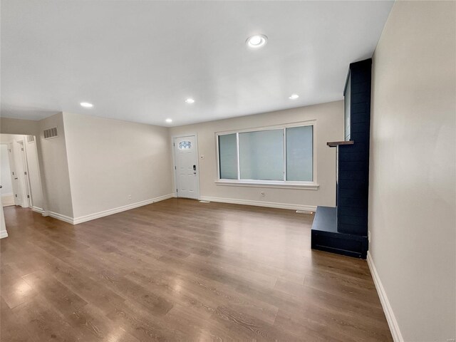 unfurnished living room with hardwood / wood-style flooring and a wood stove