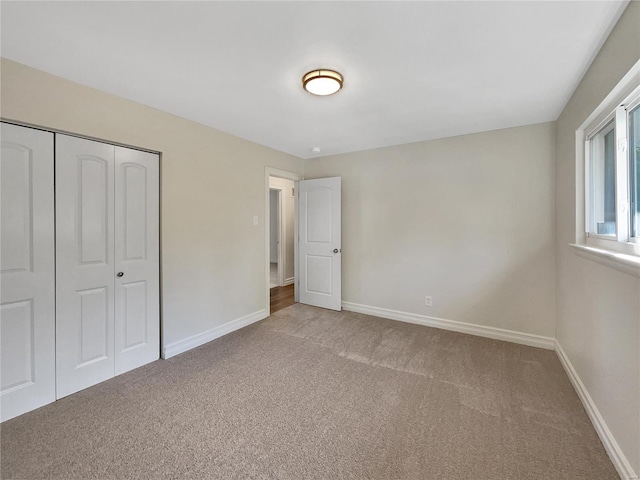 unfurnished bedroom featuring light carpet and a closet