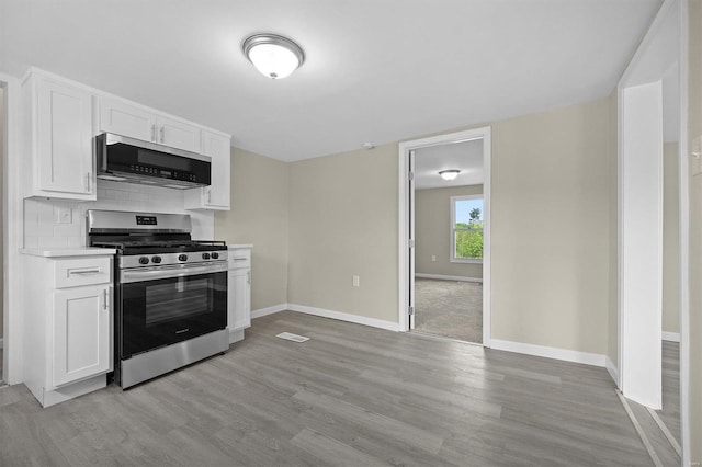 kitchen featuring tasteful backsplash, appliances with stainless steel finishes, light countertops, light wood-type flooring, and white cabinetry