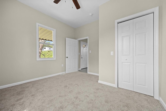 unfurnished bedroom with a closet, light carpet, ceiling fan, and baseboards