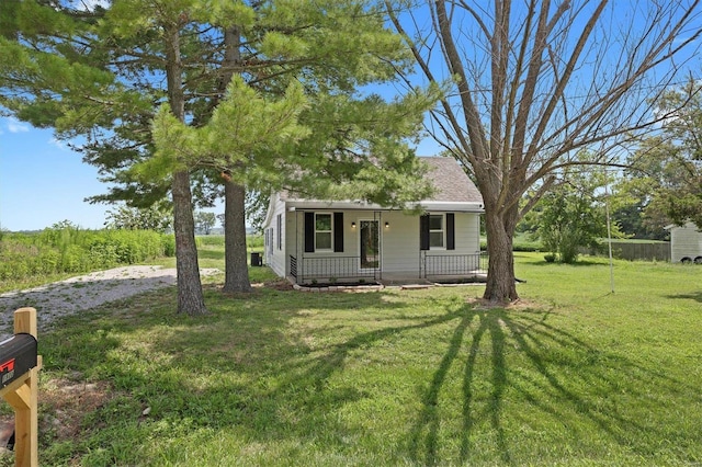 view of front of property with covered porch, a front lawn, and roof with shingles