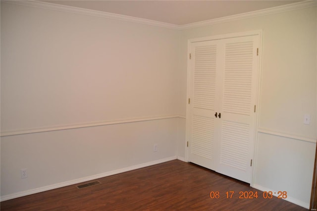 unfurnished bedroom with a closet, dark wood-type flooring, and ornamental molding