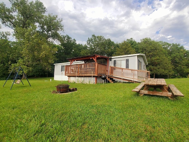 rear view of property featuring a yard, a fire pit, and a wooden deck