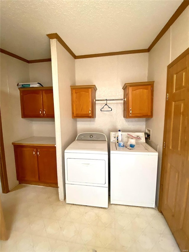 laundry room featuring cabinet space, crown molding, a textured ceiling, light floors, and washing machine and dryer