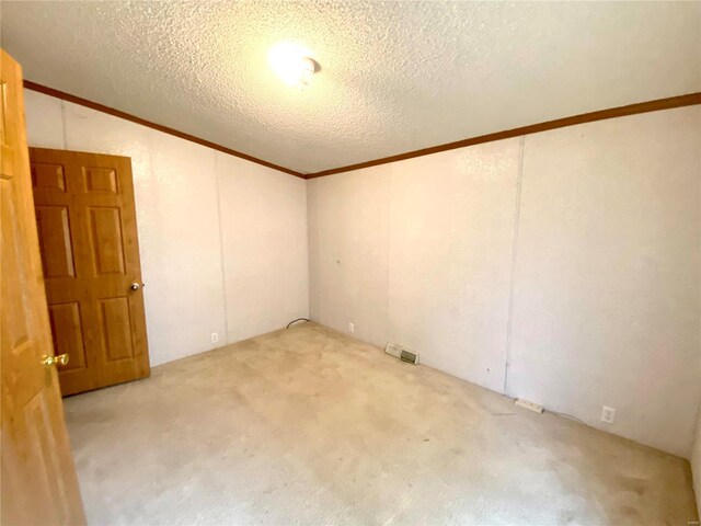 carpeted empty room featuring a textured ceiling, lofted ceiling, and crown molding