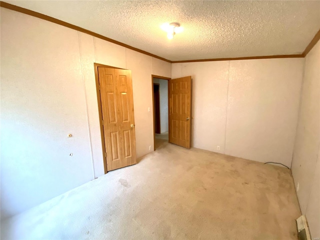 unfurnished room featuring carpet, crown molding, and a textured ceiling