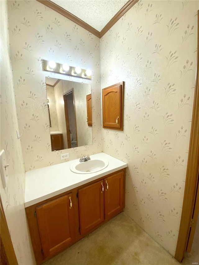 bathroom with a textured ceiling, toilet, vanity, wallpapered walls, and crown molding