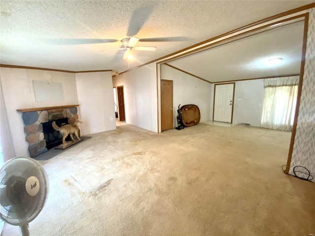 carpeted living area featuring a textured ceiling, ceiling fan, a stone fireplace, vaulted ceiling, and ornamental molding