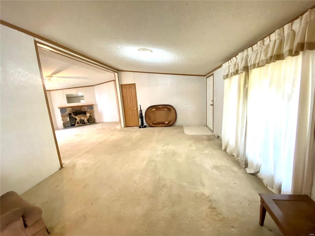 basement featuring ornamental molding, a stone fireplace, carpet flooring, and a textured ceiling