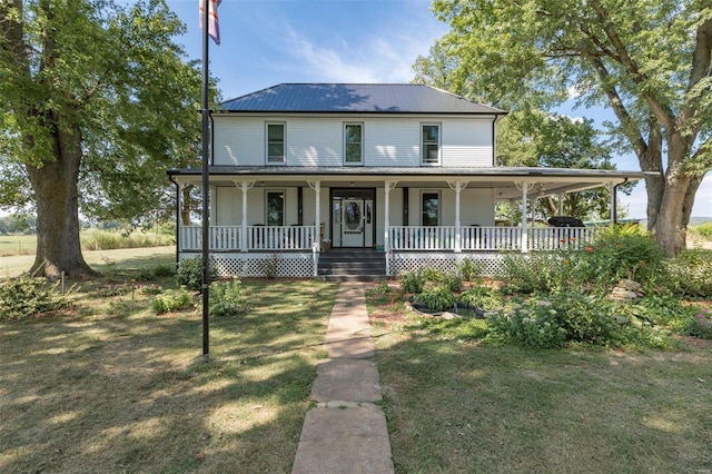 farmhouse inspired home featuring covered porch, a front lawn, and metal roof