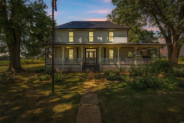 farmhouse inspired home with covered porch, a yard, and metal roof