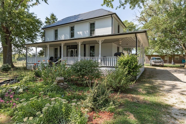 farmhouse featuring covered porch, metal roof, and driveway