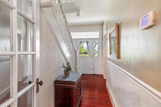 entryway with a textured wall, dark wood-type flooring, stairway, and baseboards