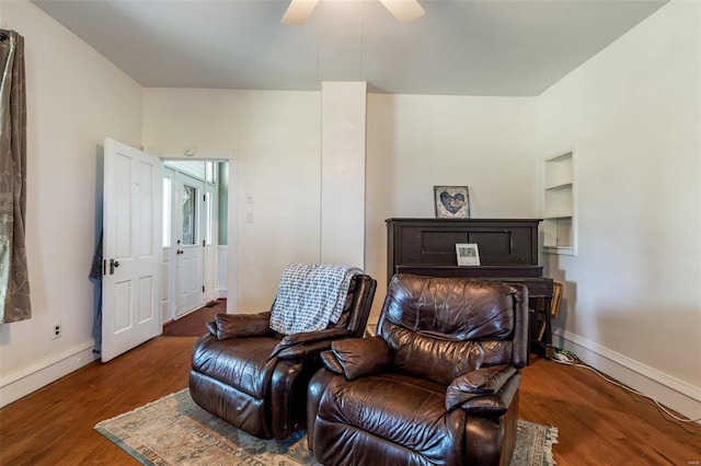 living area with dark wood-type flooring, a ceiling fan, and baseboards