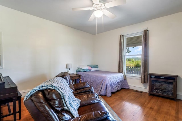 bedroom featuring visible vents, ceiling fan, baseboards, and wood finished floors