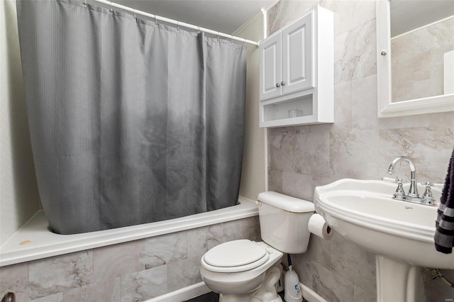 bathroom with shower / bath combination with curtain, a sink, tile walls, and toilet