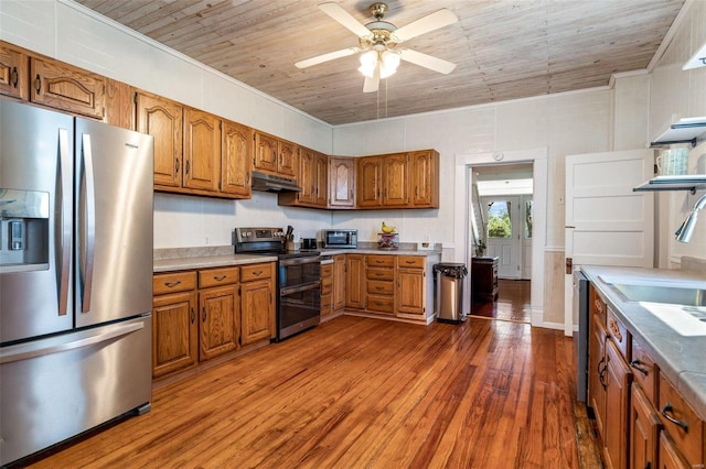 kitchen featuring appliances with stainless steel finishes, brown cabinets, dark wood-style flooring, light countertops, and under cabinet range hood