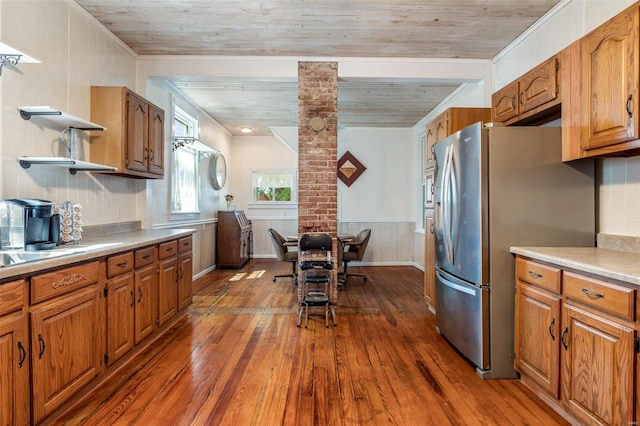 kitchen featuring dark wood-style floors, open shelves, light countertops, brown cabinetry, and freestanding refrigerator