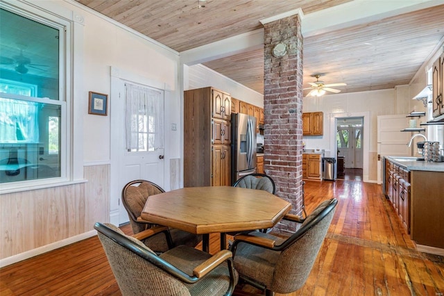 dining room featuring decorative columns, wainscoting, wood ceiling, ceiling fan, and wood finished floors