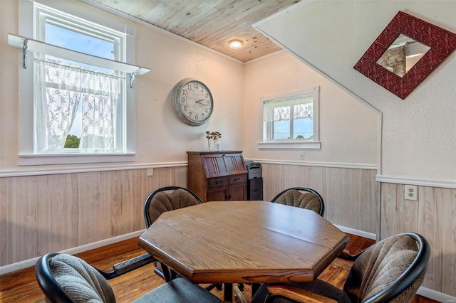 dining room featuring wooden ceiling, wainscoting, wooden walls, and wood finished floors