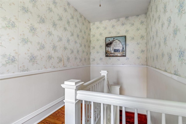 stairs featuring baseboards, wainscoting, wood finished floors, and wallpapered walls