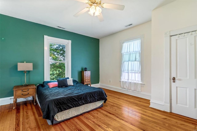 bedroom featuring baseboards, visible vents, ceiling fan, and wood finished floors